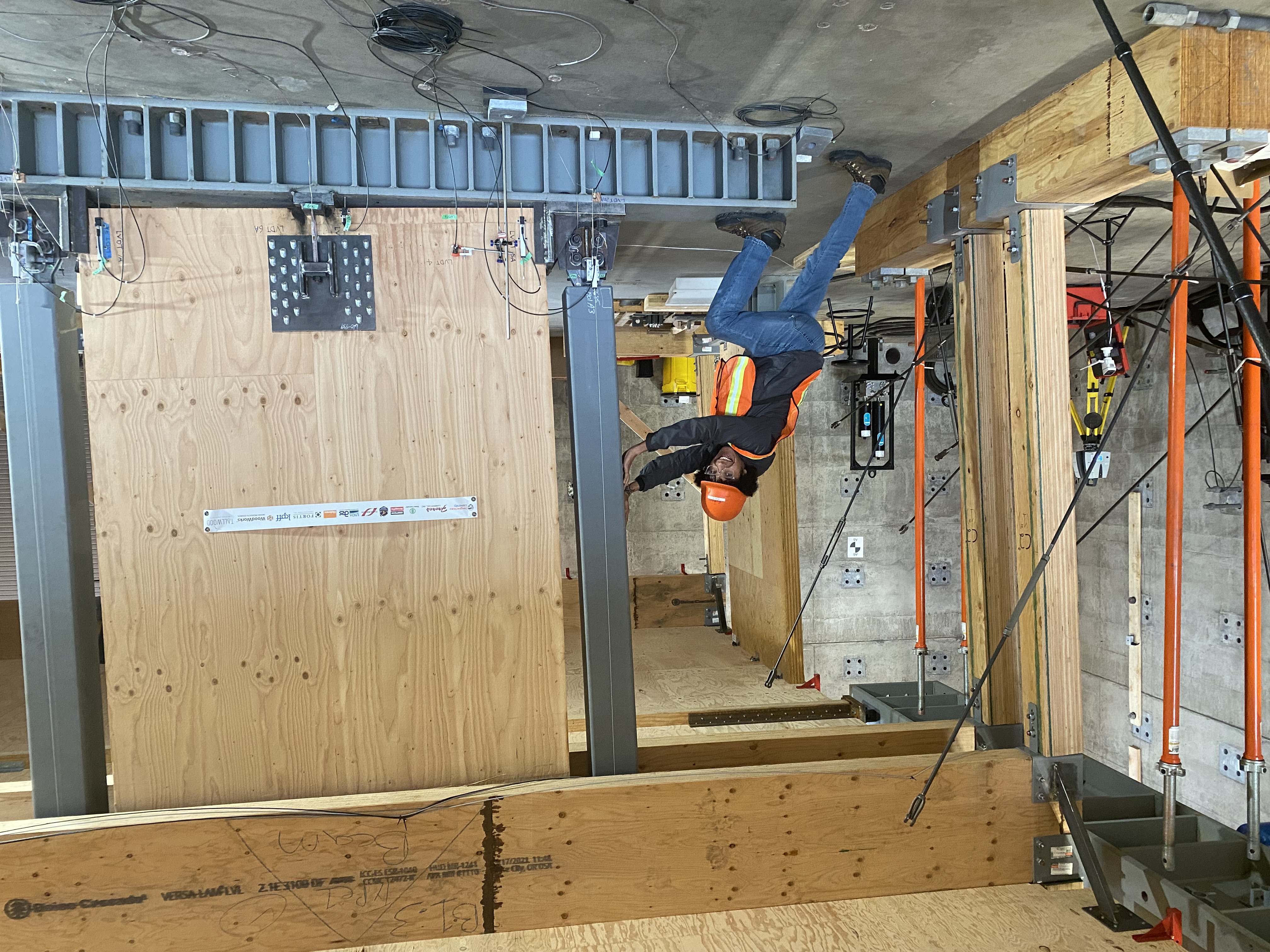 Gustavo A. Araújo R. leaning against the three-story mass timber pivoting-wall test specimen at the Oregon State University structural laboratory.